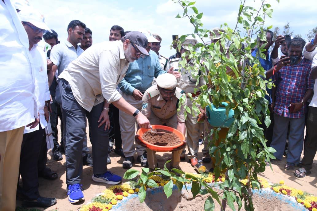 Naga Babu filling soil around a newly planted sapling in Bapatla district with forest officials looking on
