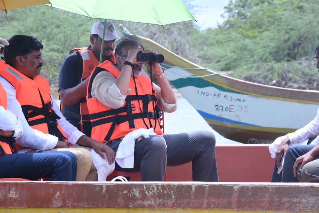 Naga Babu observing the shoreline and mangrove growth through binoculars from the survey boat