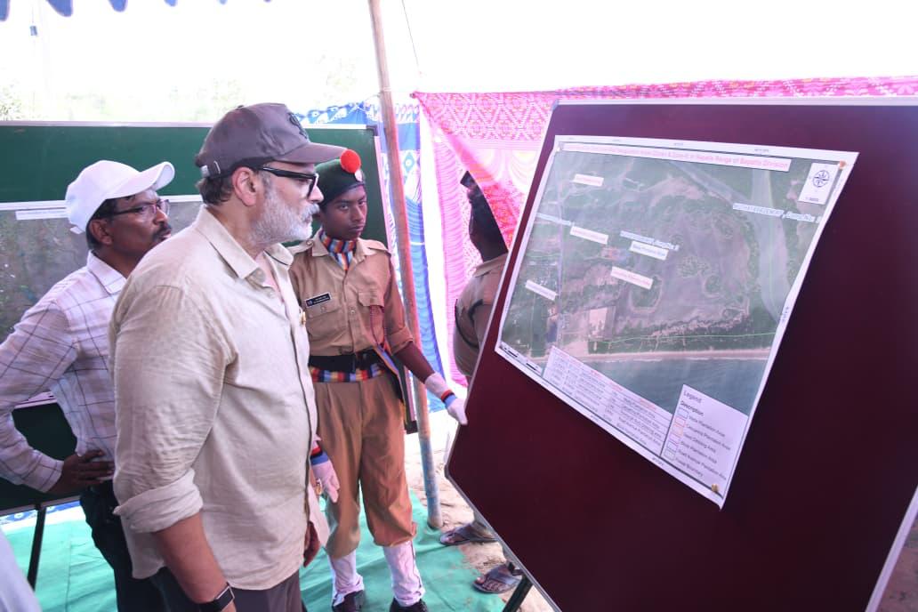 Naga Babu reviewing a satellite map of the coastal mangrove and plantation cover with forest officials and an NCC cadet