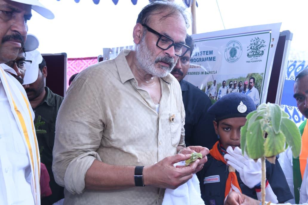 Naga Babu examining a sapling leaf with a scout at the mangrove ecosystem programme nursery display in Bapatla